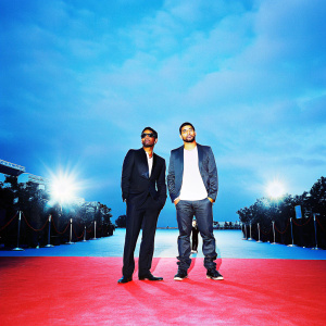 Aziz Ansari and Drake at a promotional event for 'Bing'. Red carpet setting, with bright lights and paparazzi.
