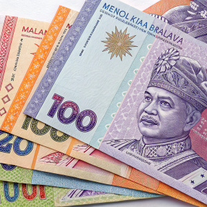 Stacked Malaysian currency notes, featuring the monarch's portrait, arranged in an artistic collage. Various denominations from 100 ringgit, with vibrant purple, white, blue, and orange hues, creating a textured, layered effect.