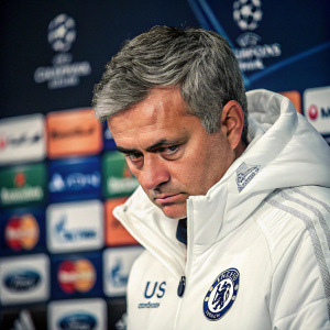Jose Mourinho, former football manager, in a sharp close-up. Dressed in a white jacket with a prominent logo. Intense gaze, slightly looking downwards. Background filled with sleek, modern logos of Mastercard, Unicredit, and Ford.