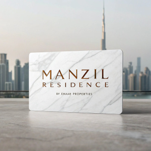 Business card for Manzil Residence by Emaar Properties. Sleek design featuring Downtown Dubai skyline in the background. White card with brown text for property name and developer. Marble texture, neutral colors, and a clean layout convey luxury and professionalism.