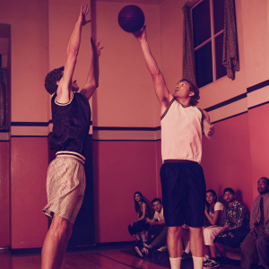 Goran Dragic and Chris Kaman mid-game leap for the basketball in a crowded gymnasium. Spectators cheering loudly