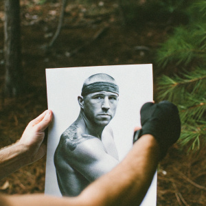 George St-Pierre, MMA fighter, depicted in a detailed pencil sketch. Realistic style, grayscale. Muscular build, wearing headband. Chinese character tattoo visible on arm. Plain white paper background, monochromatic tone, focusing on face and upper body.