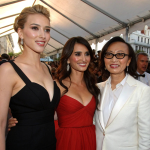 Scarlett Johansson, Penelope Cruz, and Soon-Yi Previn posing together at an outdoor film festival. Woody Allen in the background.