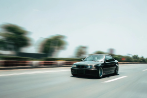 A photo Taken outside the window of a moving car on the highway of a 2004 BMW M3, film photo, old photo