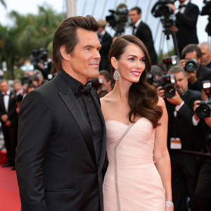 Josh Brolin and Megan Fox at Cannes Film Festival. They are standing on a red carpet surrounded by flashing cameras and paparazzi.