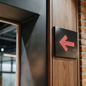 Minimalist design of an exit sign. Bold red arrow pointing right on a stark black background