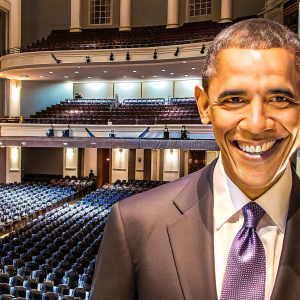 Barack Obama, ex-president, broad smile. Formal suit, purple patterned tie. Empty auditorium background