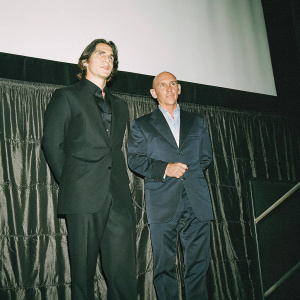 Christian Bale and Ben Kingsley attending a film premiere. Dark suits against a black backdrop.