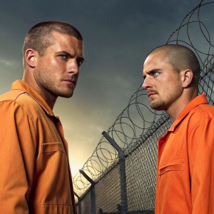 Promotional image for Prison Break. Michael Scofield and Lincoln Burrows in a tense moment, dressed in orange jumpsuits. Barbed wire fence in the background.
