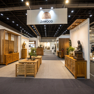 Trade show booth for Zawood. Brightly lit with wooden furniture and sculptures. Carpeted floor, visible backdrop with logo.