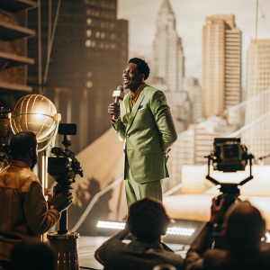 Scottie Pippen in a vibrant green suit, addressing the media at a sports awards show. Flashing cameras, cityscape backdrop.