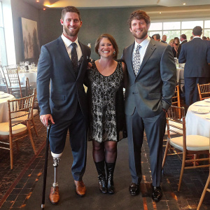 Noah Galloway, Ellen Levine, and Jamie Boyd, dressed formally, at the HELP USA Hero Awards Dinner. HELP USA branded backdrop behind them.