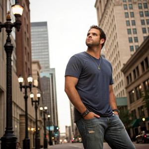 Mike Moustakas, looking intense, dressed in a casual t-shirt and jeans. Urban street background