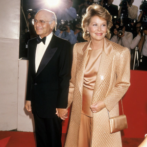Norman Lear and Ellen Lear at an awards show, both wearing elegant attire. Red carpet with paparazzi in background
