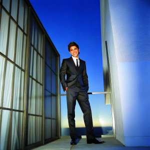 Zach Efron on the cover of GQ magazine. Stylish black suit, smiling confidently. Luxurious background