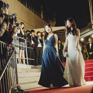 Kwon Yu-Ri and Shin Sae-Kyung, South Korean actresses, at the Cannes Film Festival premiere. Kwon Yu-Ri in a deep blue evening gown, Shin Sae-Kyung in a simple white dress. Nighttime glamour on the red carpet.