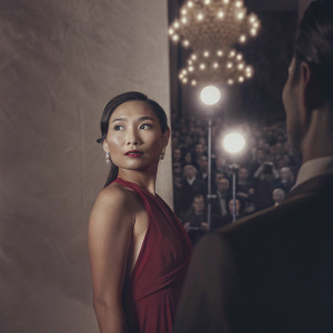 Hong Chau, Asian actress, dressed in a vibrant red dress, at an awards ceremony. Crowded event background, bright lights.