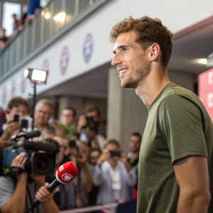 Leon Goretzka, soccer player, in a casual green t-shirt. At a press conference for Bayern Munich. Crowd in background