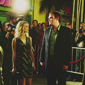 Melanie Laurent and Quentin Tarantino at a bustling Hollywood event. Surrounded by flashing cameras and curious onlookers.