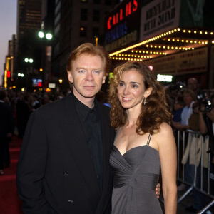 David Caruso and Margaret Buckley attend the opening night of 'Steal This Movie' at a bustling theater in New York City. Caruso in a black suit, Buckley in a stylish dress.