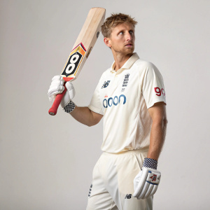 Cricket player Joe Root, intense expression, holding a cricket bat. White shirt, number 9000 on jersey. Sponsor logos visible.