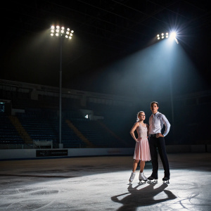 Aliona Savchenko and Bruno Massot, posing in the middle of an empty ice rink. Nighttime, spotlights illuminating them