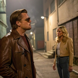 Leonardo DiCaprio and Brad Pitt in a gritty alleyway scene from Once Upon a Time in Hollywood. Blonde actress in background, smoking a cigarette