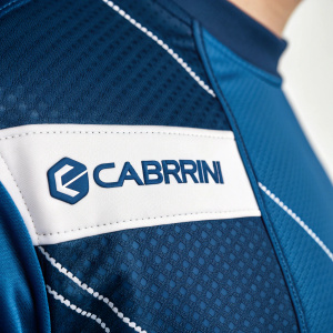 A detailed image of Carbrini sports attire. Focus on the logo section. Blue fabric with white 'Carbrini' label in clean, modern font.