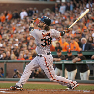 Michael Morse, baseball player, mid-swing in a packed stadium. Focused look, gray and orange uniform. Number 38 visible