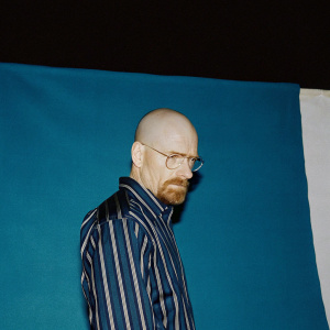 Digital art of Walter White aka Heisenberg. Caucasian male, bald head, strong jawline, well-groomed beard, striped shirt, button-up collar. Intense gaze against a stark black backdrop.