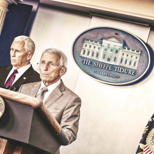 Anthony S. Fauci and Mike Pence at a White House podium. Fauci stands in front, Pence behind. White House emblem visible on backdrop.