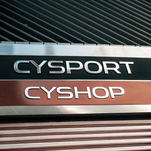Promotional banner for CYSPORT featuring sleek, bold numbers and website links for CYSPORT and CYSHOP. Dark blue and metallic grey background, modern and athletic design.