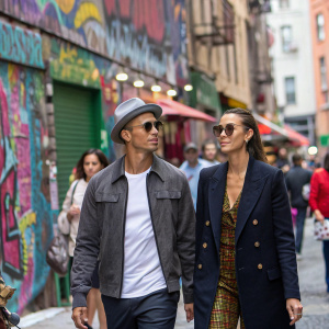 Cristiano Ronaldo and Irina Shayk, walking through crowded city street, vibrant street art backdrop