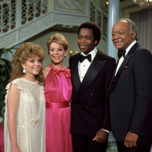 Cast of Diff'rent Strokes: Dana Plato, Charlotte Rae, Conrad Bain, and Gary Coleman at a glamorous event. Vintage decor and sophisticated attire in vivid color.