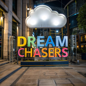 Dream Chasers logo. Vibrant logo with cloud graphic floating above text. Dark blue backdrop