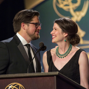 Rich Sommer and Virginia Donohoe sharing a moment at the awards ceremony. Rich in dark suit, glasses, and beard. Virginia in black dress and green necklace.