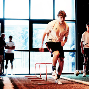 Charles De Ketelaere, wearing AC Milan jersey, in intense training session at the club's state-of-the-art facility.