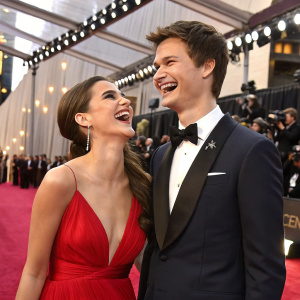 Violetta Komyshan and Ansel Elgort laughing together at the Oscars. Wearing formal attire, elegant red carpet setting.