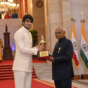 Neeraj Chopra, in formal attire, receiving Arjuna Award from President Ramnath Kovind. Ceremony backdrop