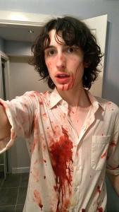 Finn Wolfhard looking at the camera, selfie, covered in blood, showing armpits, stinky armpits, smelling his armpits, shirtless and sweaty