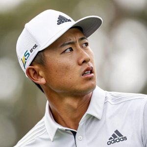 Golfer Collin Morikawa, intense look, wearing white hat and Adidas shirt. Background is blurred, focus on his face