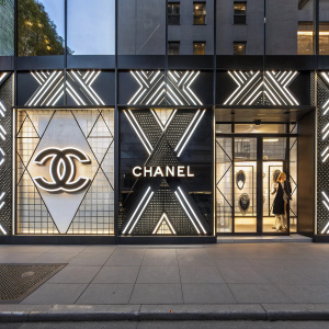 High-end boutique window display featuring Chanel's iconic logo amidst sleek geometric patterns and glossy surfaces.