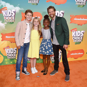 Cooper Barnes, Ella Anderson, Riele Downs, and Sean Ryan Fox at the Nickelodeon Kids' Choice Awards 2016. They are posing on an orange carpet surrounded by Kids' Choice Awards branding and logos.