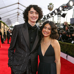 Finn Wolfhard and Sarah Roberts on the SAG Awards red carpet, smiling for the cameras.
