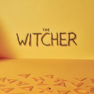 Title screen for 'The Witcher' TV series. Dark, ominous, cursive font in shades of gray. Graffiti style backdrop with graphic elements.