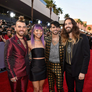 DNCE band members Cole Whittle, JinJoo Lee, Joe Jonas, and Jack Lawless at a glitzy awards ceremony. Red carpet event with vibrant crowd