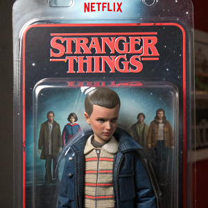 Collectible action figure packaging featuring Eleven from Stranger Things. Clear plastic window displaying Eleven and other characters. Netflix logo and Stranger Things title prominently displayed