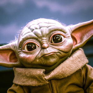 Close-up of Baby Yoda, a character from The Mandalorian. Wrinkled skin, wide eyes, and unique facial features. Dark background to emphasize details