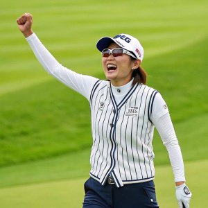 Mayu Hosaka, a celebrated golfer, grinning widely while standing amidst the lush green golf course. She wears a stylish white striped vest, sunglasses, and a white cap, celebrating her recent victory.
