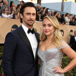 Milo Ventimiglia and Hayden Panettiere at the award show. They are dressed formally, Ventimiglia in a tuxedo, Panettiere in a silver gown. Background filled with cheering crowd.